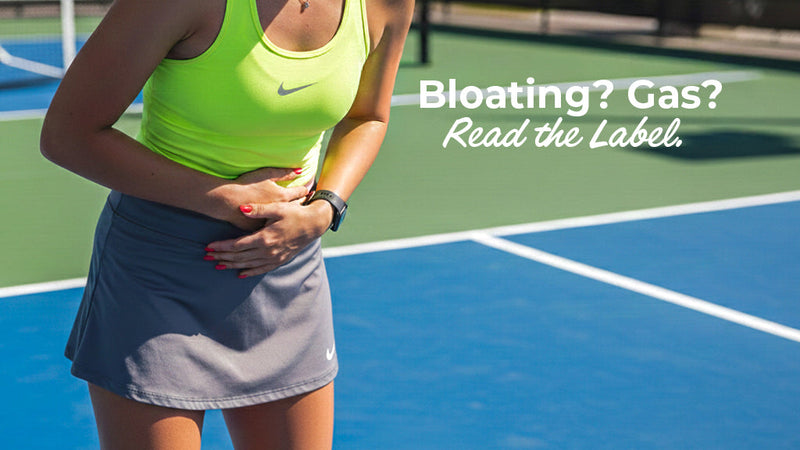 A female athlete on a pickleball court clutching her stomach in discomfort with the text overlay "Bloating? Gas? Read the Label." This visual emphasizes how certain ingredients in sports drinks can lead to digestive distress during physical activity.