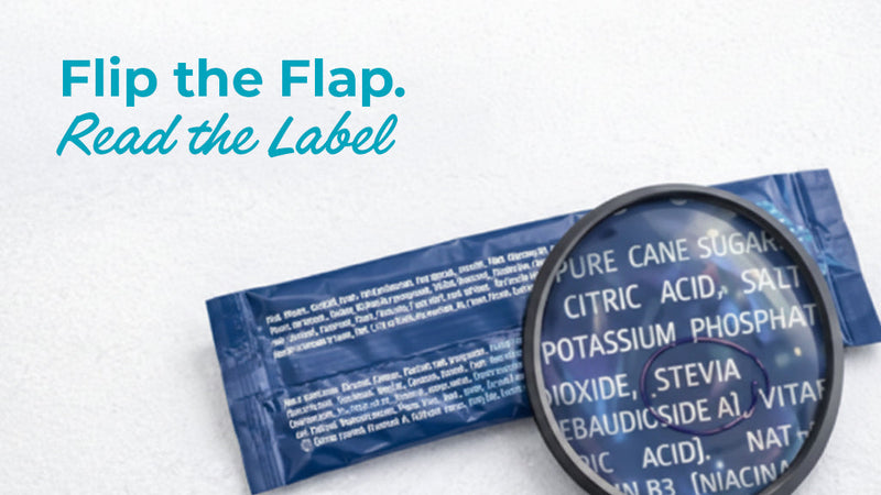 A magnifying glass hovering over the ingredient list of a hydration packet, highlighting terms like "Pure Cane Sugar" and "Stevia," with the text "Flip the Flap. Read the Label" to encourage consumer awareness of hidden irritants.