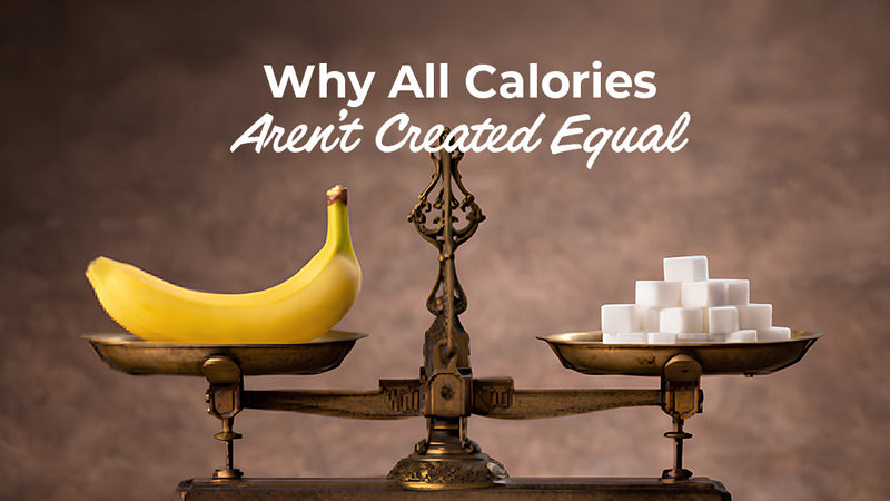 An image titled "Why All Calories aren't created equal." A metal scale balances whole foods like a coconut and bananas on the left against a cheeseburger, energy drinks, and sugar cubes on the right. The scale tips heavily toward the processed foods.